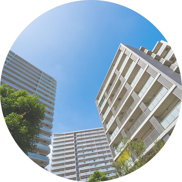 青空の下に建つオフィスビルとマンションの外観